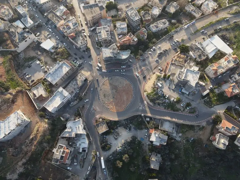 Drone aerial view of an urban traffic circle surrounded by city buildings and roads.