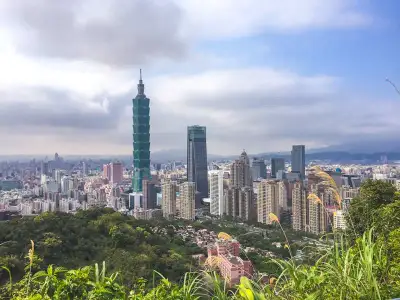A breathtaking aerial view of Taipei City and Taipei 101 surrounded by urban skyscrapers and lush greenery.