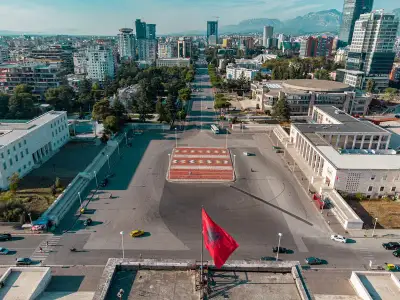 Aerial view of Skanderbeg Square in Tirana, Albania, featuring the iconic Albanian flag and cityscape.