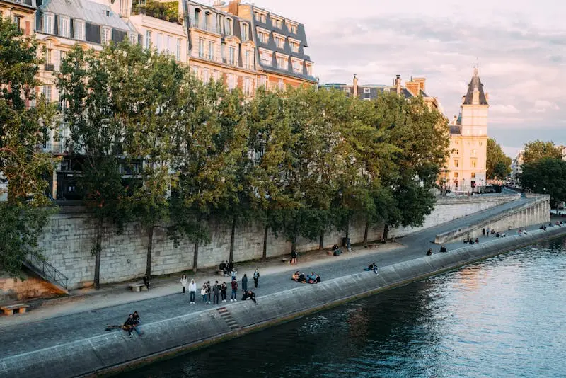 Charming riverside promenade in Paris with historic architecture and people enjoying their day.