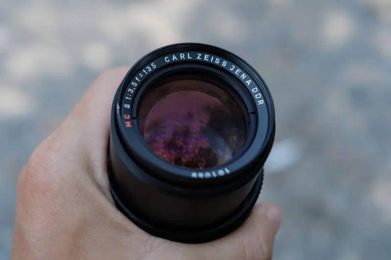 Close-up view of a Carl Zeiss Jena camera lens being held. Perfect for photography themes.