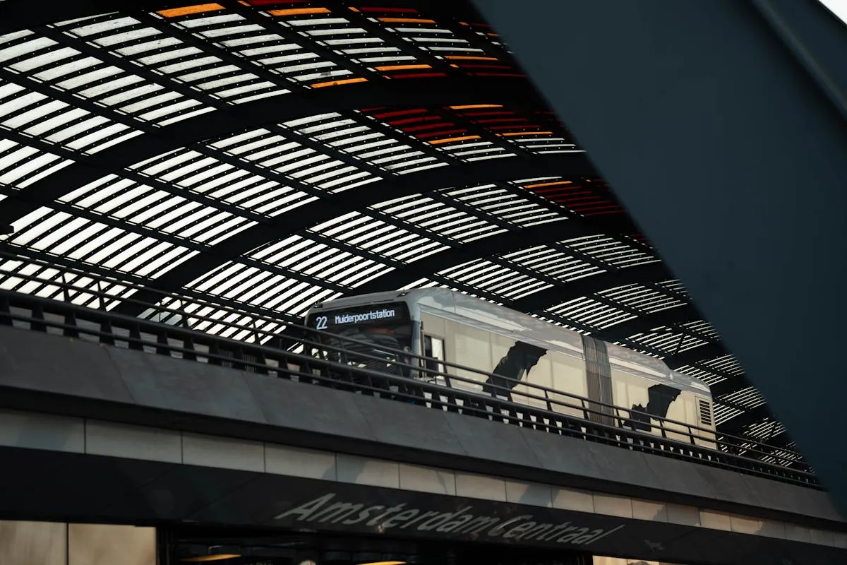 Train at Amsterdam Central Station under the modern, geometric roof structure.