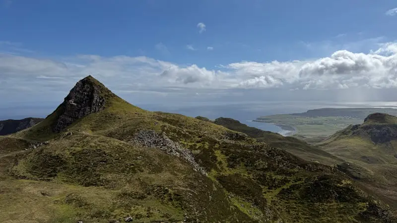 Beautiful landscape of Quiraing on the Isle of Skye, showcasing rolling hills and a clear blue sky.