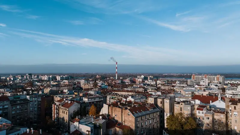 Aerial cityscape of Beograd, Serbia featuring urban skyline and smokestack.
