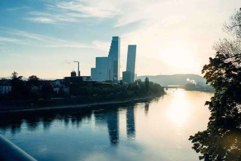 Captivating Basel skyline with modern architecture reflected in the Rhine at sunset.
