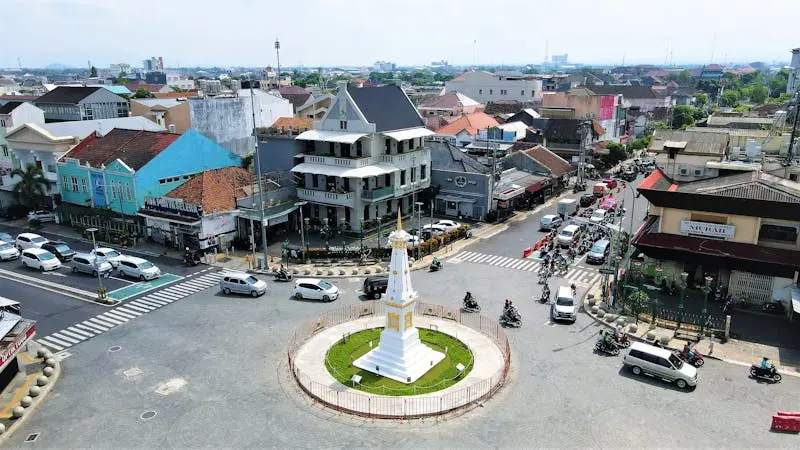 A vibrant aerial view of the Tugu monument in Yogyakarta, Indonesia, with bustling city life.