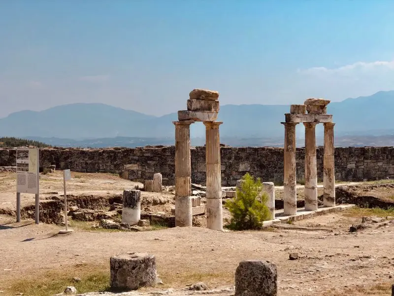 Explore ancient Roman ruins in Hierapolis, Turkey under a clear blue sky, showcasing historic columns and pillars.