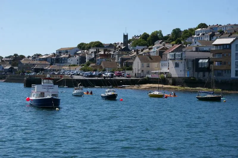 Charming coastal townscape with boats in a harbor under sunny skies.