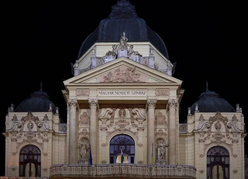 Stunning nighttime view of the illuminated facade of the National Theatre in Pécs, Hungary.