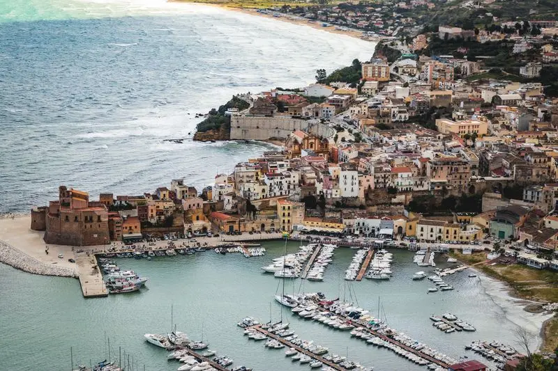A picturesque aerial shot of a coastal town in Sicily, showcasing the marina and historic architecture.