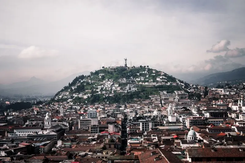 Aerial view of Quito featuring Panecillo Hill and Virgin statue, capturing historic architecture and vibrant cityscape.